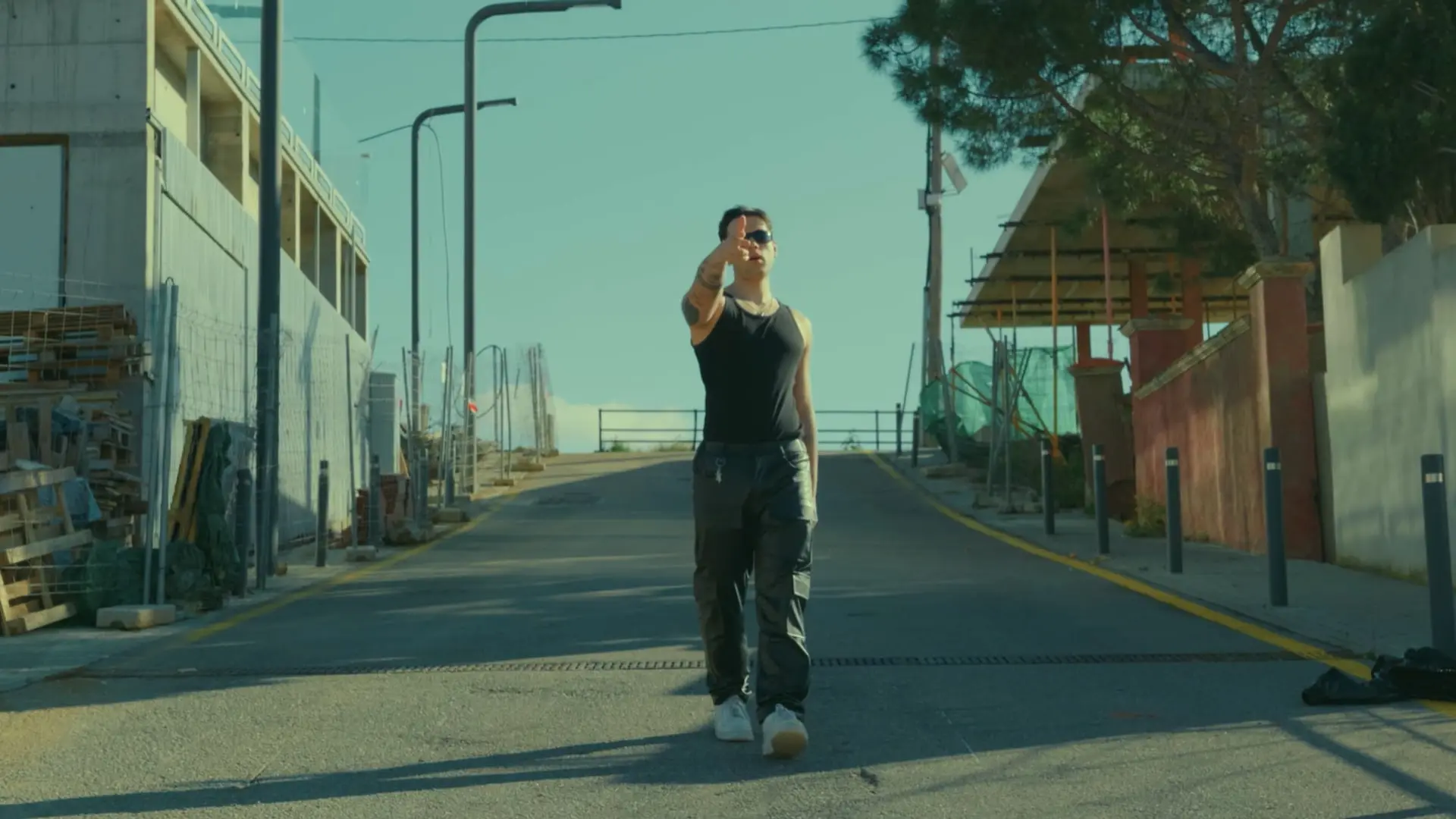 Fotograma del videoclip de Glaecy: el artista camina hacia la cámara por una calle soleada, con dirección de cámara de Eloi Cotonat
